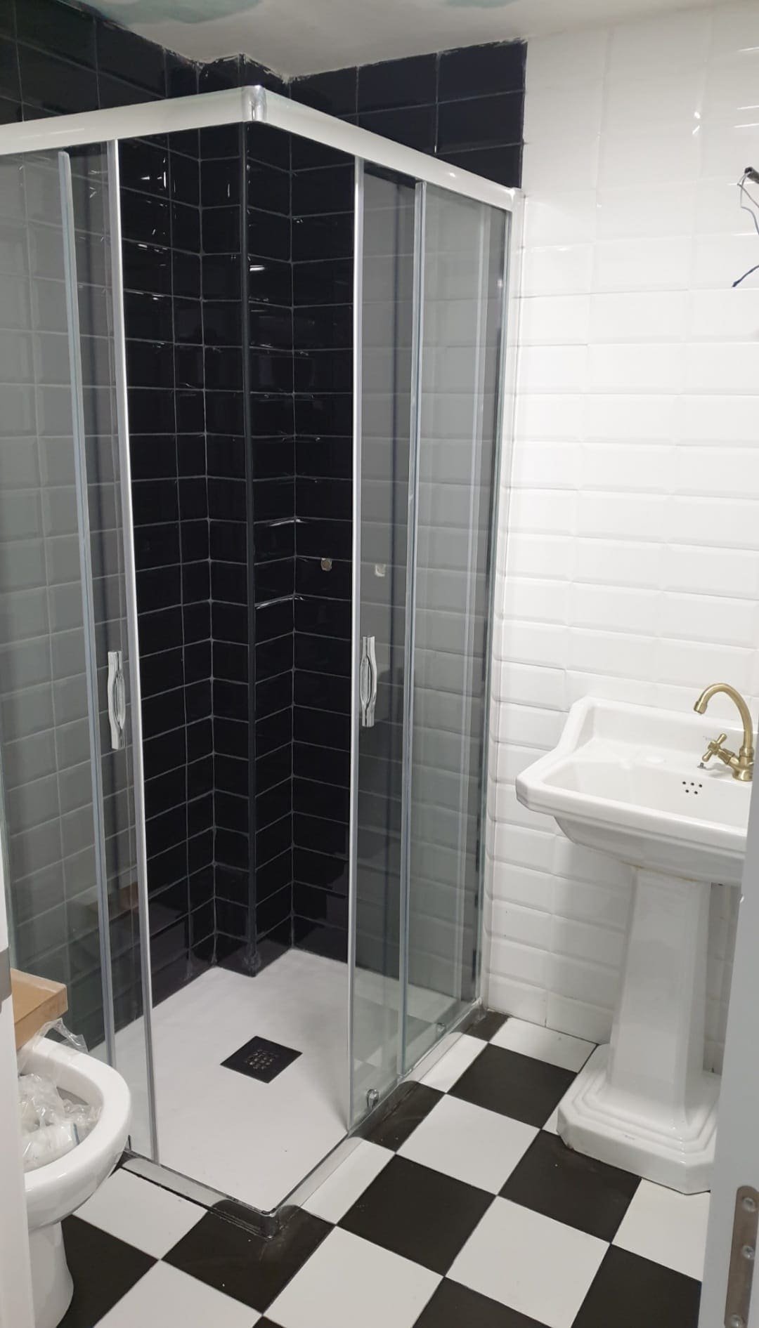 Baño con zona de ducha renovada en blanco y negro