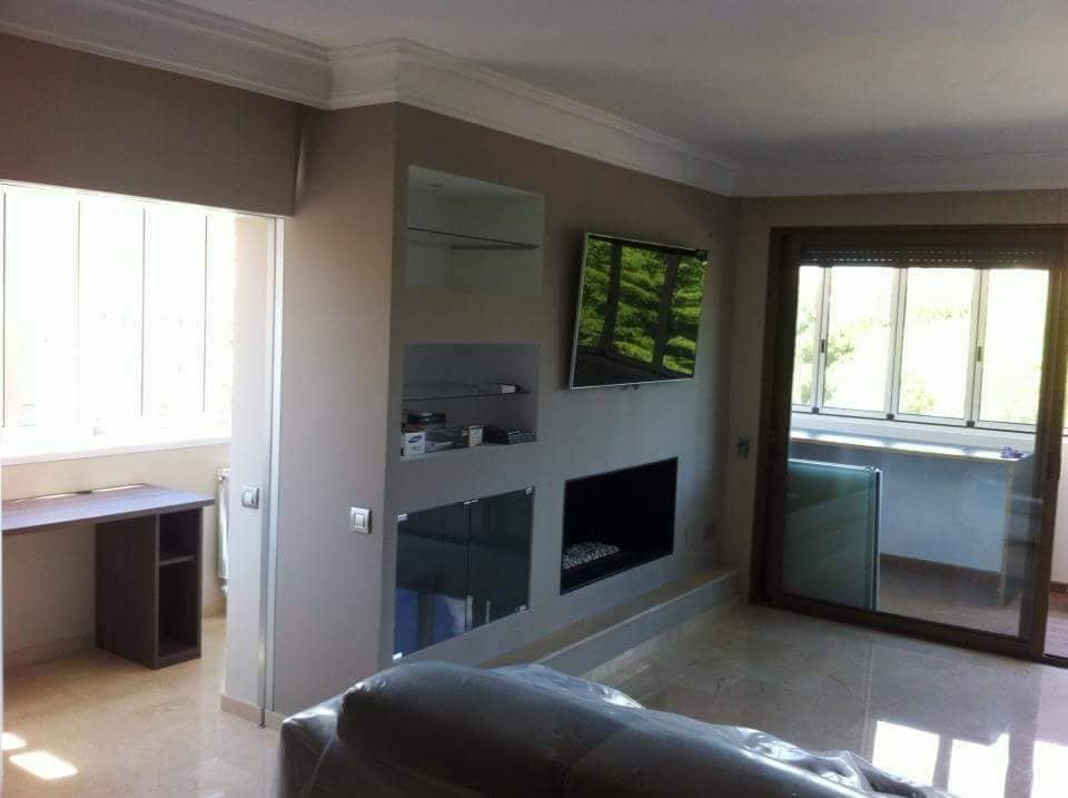 Salón reformado con mueble integrado para televisión y grandes ventanas