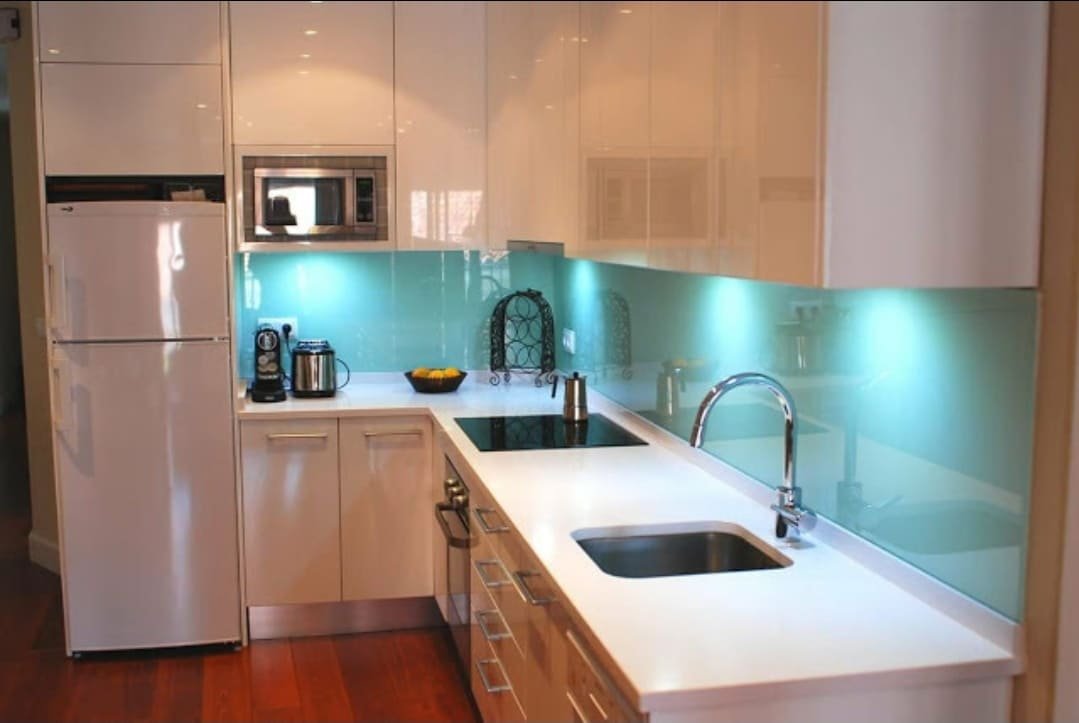 Cocina reformada con muebles claros, encimera blanca e iluminación integrada