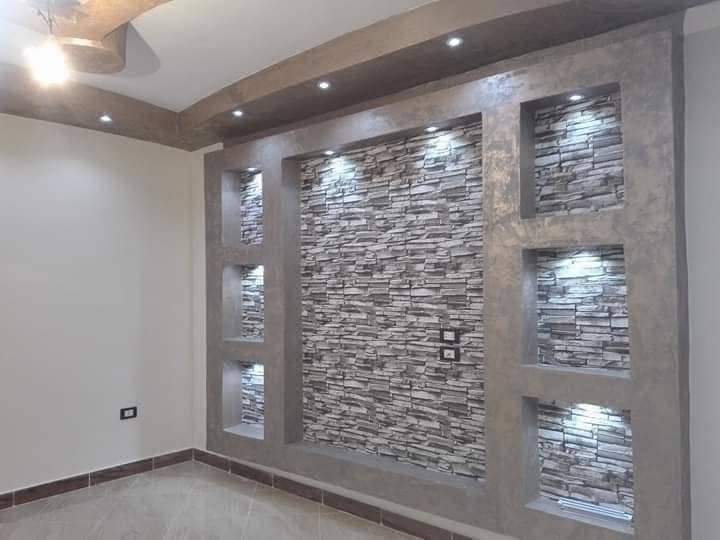 Pared decorativa terminada con revestimiento de piedra e iluminación empotrada
