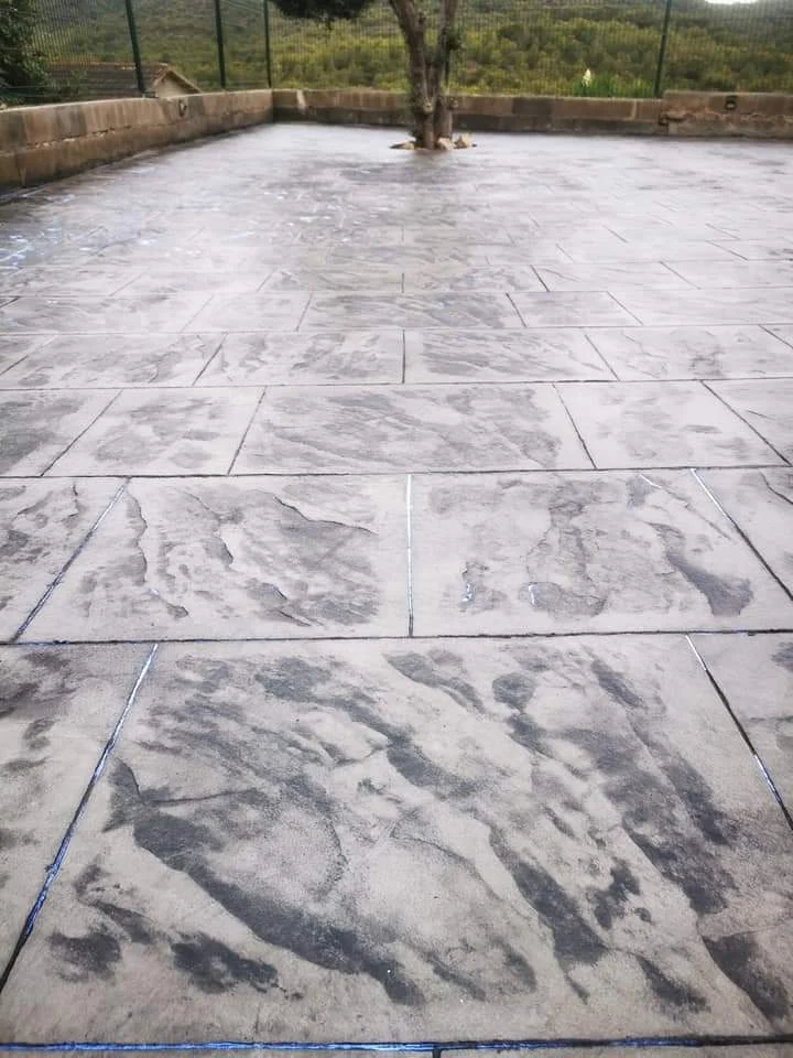 Ejecución de una amplia superficie exterior en hormigón impreso, adaptada al terreno y a los elementos existentes, con un acabado decorativo que combina resistencia y estética.