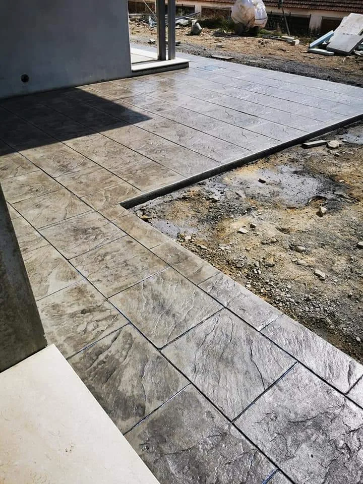 Pavimento de hormigón impreso realizado en una terraza y zona de paso exterior, con textura efecto piedra y acabado gris pensado para integrarse con el entorno de la vivienda.