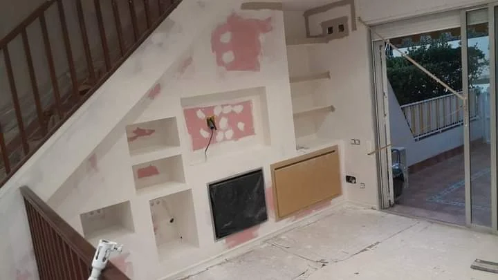 Fase de acabado del mueble de pladur bajo la escalera, con huecos y estanterías a medida, juntas tratadas y superficies preparadas para el acabado final.